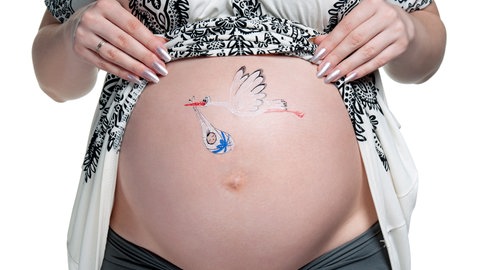 Bauch einer schangeren, darauf gemalt ein Storch, der ein Baby bringt, das in weiße Tücher verpackt ist, die mit einem blauen Band gehalten werden: Es gibt sehr viele Mythen oder Ammenmärchen in Bezug auf die Schwangerschaft. Sehr viele davon beschäftigen sich mit der Prädiktion, also mit der Vorhersage des Geschlechts.