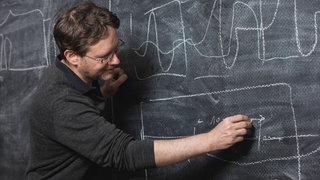 Mann schreibt an Tafel