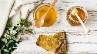 Honiggläser und Wabe: Krebspatienten sollten möglichst wenig Industriezucker zu sich nehmen und bei Süßhunger lieber zu Marmelade oder Honig greifen. 