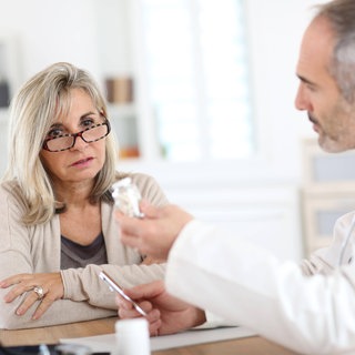 Ein Arzt berät eine Patientin und informiert über ein Medikament: Ibuprofen, Diclofenac oder Paracetamol können bei Arthrose Schmerzen lindern. Man darf sie aber nicht über Wochen oder Monate einnehmen, ohne dass das ärztlich begleitet wird.