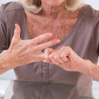 Eine Frau bewegt ihre schmerzenden Finger: Der Knorpel wird durch die Gelenkflüssigkeit ernährt, die im Gelenk gebildet wird. Das geschieht durch die Gelenkinnenhaut. Sport und Bewegung ist daher wichtig, denn so gelangen die Nährstoffe in Kontakt mit dem hyalinen Gelenkknorpel.