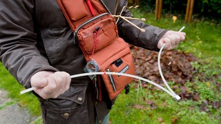 Ein Rutengänger mit Wünschelrute auf der Suche nach einer Wasserader