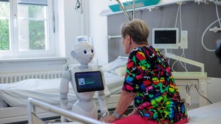 Eine Patientin spricht mit einem humanoiden Roboter. Durch Künstliche Intelligenz könnte in dieser Weise in der Zukunft etwa die Anamnese in Krankenhäusern revolurtioniert werden.