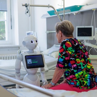Eine Patientin spricht mit einem humanoiden Roboter. Durch Künstliche Intelligenz könnte in dieser Weise in der Zukunft etwa die Anamnese in Krankenhäusern revolurtioniert werden.