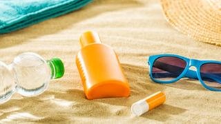 Utensilien für einen Tag am Strand liegen im Sand.