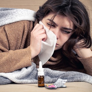 Frau ist erkältet, liegt im Bett