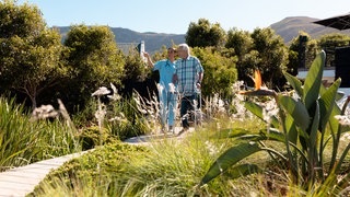 Krankenschwester läuft mit Patient mit Rollator durch den Garten