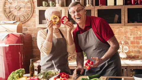 Mann und Frau stehen in der Küche mit Lebensmitteln