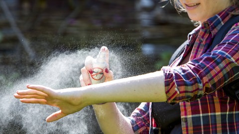 Schutz vor Mückenstich: Frau sprüht sich ein