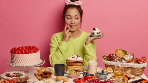 Frau mit verschiedenen süßen Lebensmitteln