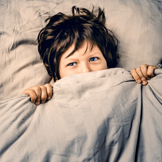 Junge liegt ängstlich im Bett