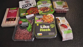 Aus einer Küchen-Oberfläche liegen mehrere Fleischersatzprodukte. Es gibt veganes Hack aus Seitan, aus Sonnenblumenkernen von der Eigenmarke von Rossmann und Hack auf Soja-Basis von Rügenwalder Mühle.