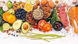 Verschiedenste Lebensmittel wie Obst Gemüse und Fisch liegen nebeneinander - vor allem Obst und Gemüse wären dabei Teil einer basischen Ernährung
