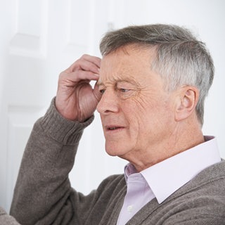 Ein Mann schaut verwirrt auf seinen Kalender. Vergesslichkeit, Konzentrationsstörungen und Verwirrtheit können erste Anzeichen von Demenz sein. Sie können allerdings auch ganz anderere Ursachen haben, zum Beispiel Vitanminmangel oder Nebenwirkungen von Medikamenten.