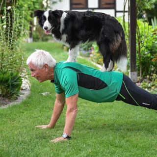 dpatopbilder - ILLUSTRATION: Jens macht am 14.06.2017 mit der Border Collie Hündin Tilda auf seinem Rücken Liegestütze im heimischen Garten in Sieversdorf (Brandenburg, gestelltes Bild). Ob Pudel, Boxer oder Golden Retriever - Anhängern des neuen Fitnesstrends «Dog Squatting» ist offenbar jeder Vierbeiner recht. Unter dem Hashtag #SquatYourDog stellen Hundebesitzer Fotos und Videos ins Netz, auf denen sie mir ihrem Hund Kniebeugen machen.