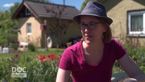 Frau mit Sonnenhut bei der Gartenarbeit