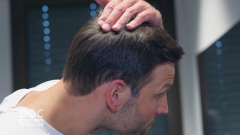 Ein Mann fährt sich durch seine Haare