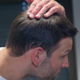 Ein Mann fährt sich durch seine Haare