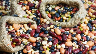 Verschiedene Hülsenfrüchte wie Bohnen, Kichererbsen, Linsen liegen auf einem Haufen. So gesund sind Hülsenfrüchte und das hilft gegen Blähungen.