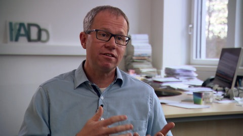 Immunologe Prof. Carsten Watzl  sitzt vor seinem Schreibtisch und erklärt etwas