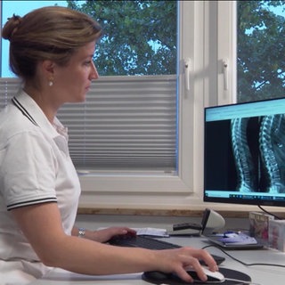 Ärztin studiert das Röntgenbild einer Wirbelsäule