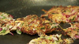 Knusprige Röstis mit roten und grünen Einsprengseln brutzeln in einer Pfanne. Rezept für knuspriges-Rettichrösti