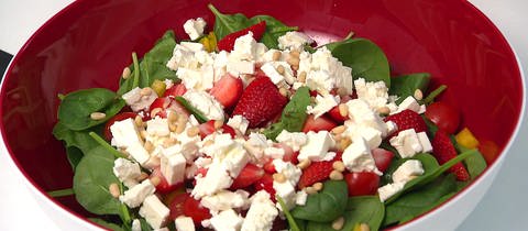 Auf dem Teller ist ein Spinatsalat mit Tomaten zu sehen. Spinat gegen Blähungen, hohen Blutdruck, Eisenmangel und für die Extra-Portion Vitamine? Wie gut Spinat wirklich ist. Und: Darf man Spinat aufwärmen? 