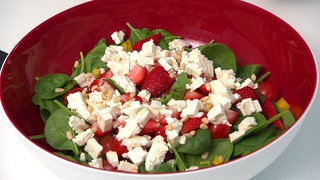 Auf dem Teller ist ein Spinatsalat mit Tomaten zu sehen. Spinat gegen Blähungen, hohen Blutdruck, Eisenmangel und für die Extra-Portion Vitamine? Wie gut Spinat wirklich ist. Und: Darf man Spinat aufwärmen? 