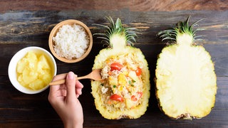 Reissalat, serviert in einer halben Ananas. Rezept für Reissalat mit Ananas, Chicorée, Paprika und Koriander