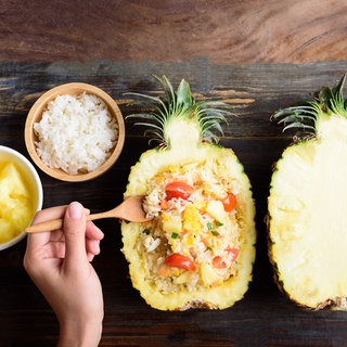 Reissalat, serviert in einer halben Ananas. Rezept für Reissalat mit Ananas, Chicorée, Paprika und Koriander