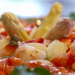 Es ist ein Spargelcarpaccio auf Babyspinat und Löwenzahn mit Erdbeer-Kapern-Vinagraitte zu sehen