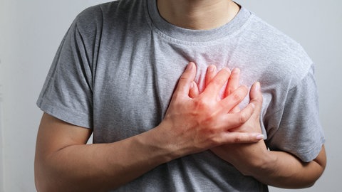 Mann greift sich mit beiden Händen ans Herz. Vorhofflimmern: Neue Behandlungsmöglichkeit mit weniger Nebenwirkungen macht Hoffnung.