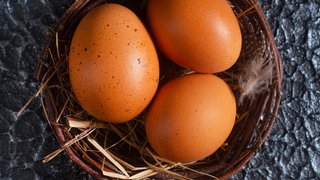 Drei braune Eier in einem Weidenkörbchen. Eier sind aus unserer Küche kaum wegzudenken - nicht nur zu Ostern. Wie lange bleibt ein Ei frisch und was bedeutet die Hennenhaltung für die Umwelt? Bio-Eier oder ganz auf Eier verzichten?