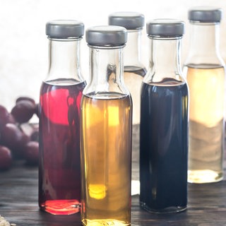 Verschiedene Sorten Essig stehen auf einem Tisch. Abnehmen, schöne Haut, tolle Haare – wie sinnvoll ist Apfelessig für die Gesundheit? Wie gut sind die Inhaltsstoffe und was ist mit anderem Essig? 