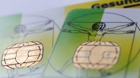 Zwei Versichertenkarten der Allgemeinen Ortskrankenkassen (AOK) liegen auf einem Tisch.