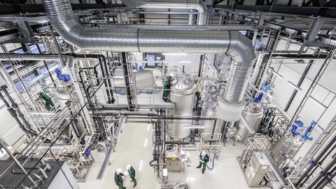 Hier stehen glänzende Tanks in einer weißen Industriehalle mit vielen Leitungen und Lüftungsrohren. Die neue Weide: Das Stuttgarter Fraunhofer-Institut für Grenzflächen- und Bioverfahrenstechnik hat für Industrietests eine Großanlage in Leuna