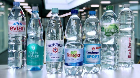 Sieben Flaschen verschiedener Mineralwasser-Hersteller stehen auf einem Tisch. Welches Mineralwasser ist das Beste? Wie gut ist Mineralwasser im Vergleich zu Leitungswasser?