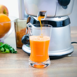 Obst- und Gemüsesäfte sind lecker und können zu Hause mit einem Entsafter selbst gemacht werden. Wie gesund sind die Säfte? Ein Entsafter presst Kartottensaft in ein Glas.