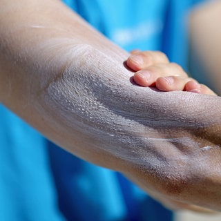 Ein Mann verreibt Sonnencreme auf seinem Arm. Viele erkundigen sich über Sonne und Wetter, aber nur wenige kennen die Werte für UV-Strahlung und die Gefahr eines Sonnenbrands.