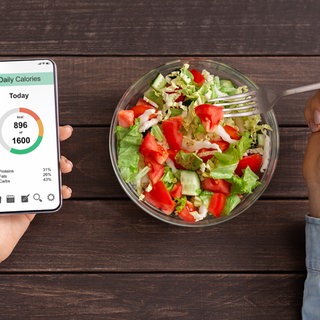 Schüssel mit Salt, daneben ein Handy mit dem Kalorien gezählt werden