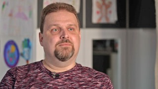Krebspatient Nico Schneider sitzt vor einer Wand.