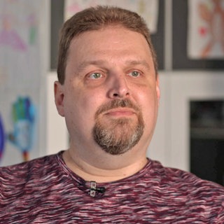 Krebspatient Nico Schneider sitzt vor einer Wand.
