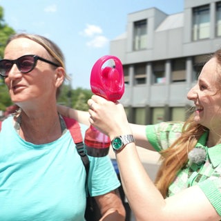 Reporterin kühlt Menschen mit Eiswürfeln und Ventilator ab