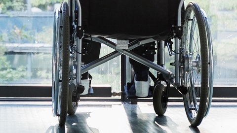 Rollstuhl vor einer Fensterscheibe