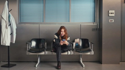 Frau sitzt im Wartezimmer und googelgt Symptome