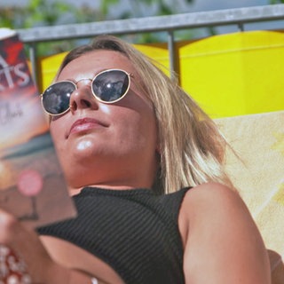 Frau liest in der Sonne ein Buch