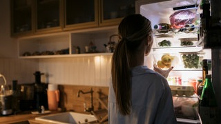Frau geht nachts an den Kühlschrank