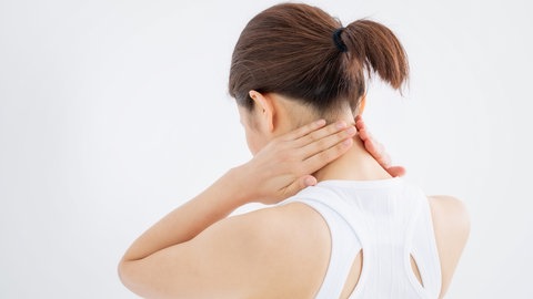 Frau greift sich in den Nacken