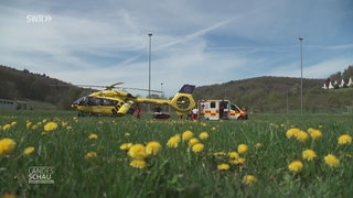 Ein Rettungs-Hubschrauber und ein Krankenwagen stehen auf einer Wiese