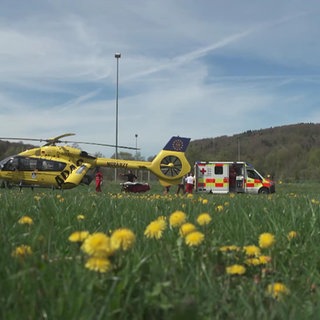 Ein Rettungs-Hubschrauber und ein Krankenwagen stehen auf einer Wiese
